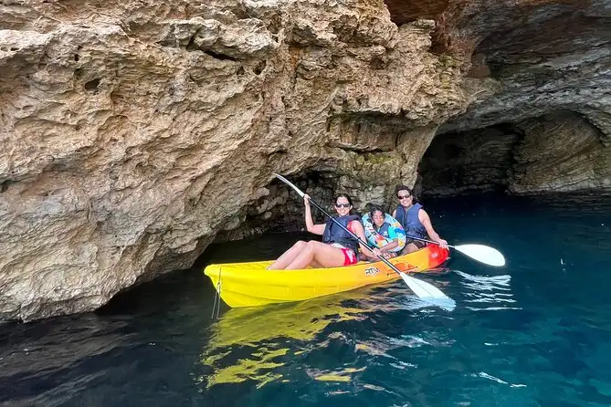Ibiza sea cave kayaking experience with people paddling through rocky coastal waters.